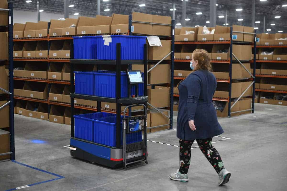 An associate follows Chuck to the next pick location in the Crocs Dayton, Ohio warehouse
